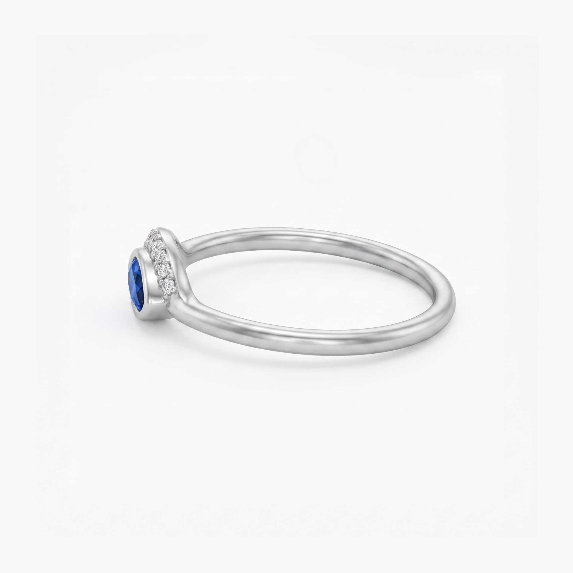 A silver ring featuring a round-cut blue sapphire center stone and a halo of small clear stones along the shank, shown on a clean white background.