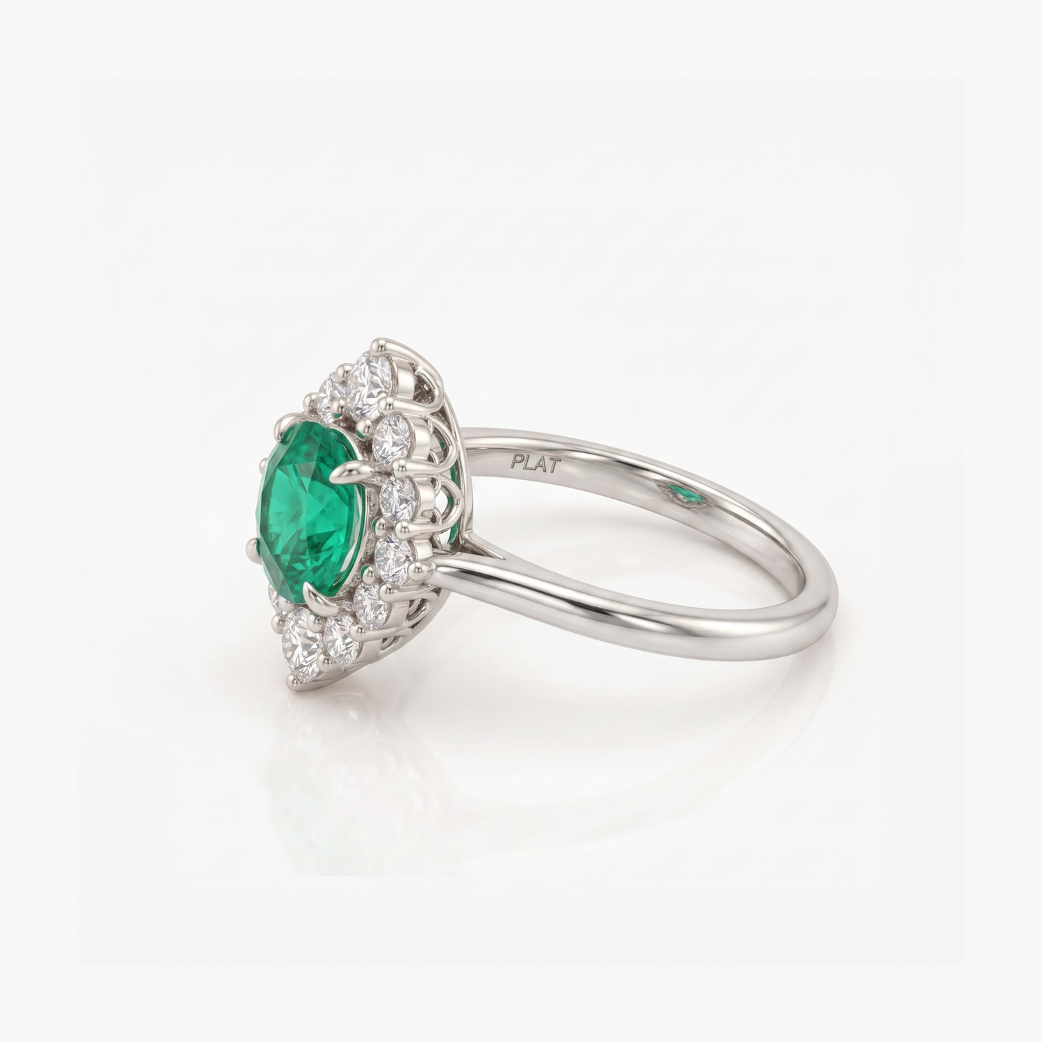 A silver ring featuring a pear-cut green emerald center stone surrounded by a halo of small clear stones, set on a polished silver band with a visible &
