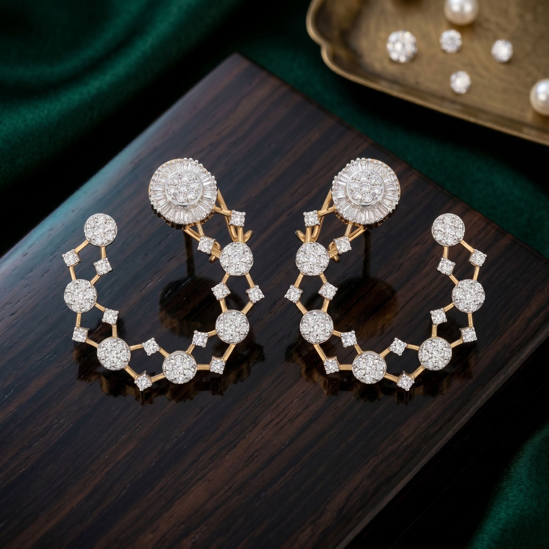 Pair of diamond earrings on a dark surface with a green fabric background