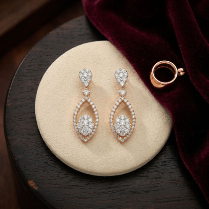 Pair of diamond earrings on a round beige cushion with a dark wooden background