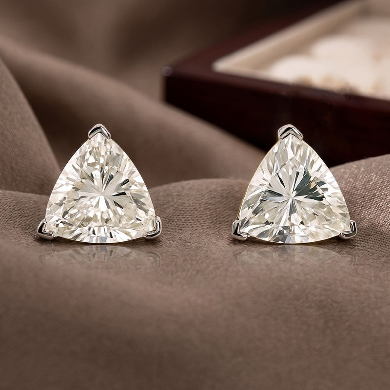 Pair of trillion-cut diamond earrings on a soft brown fabric background