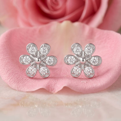 Flower-shaped lab grown diamond stud earrings on a pink satin background