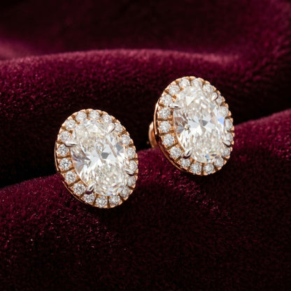 Oval halo lab grown diamond stud earrings on a burgundy velvet background