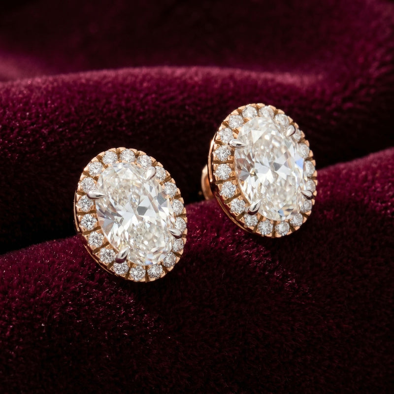 Oval halo lab grown diamond stud earrings on a burgundy velvet background