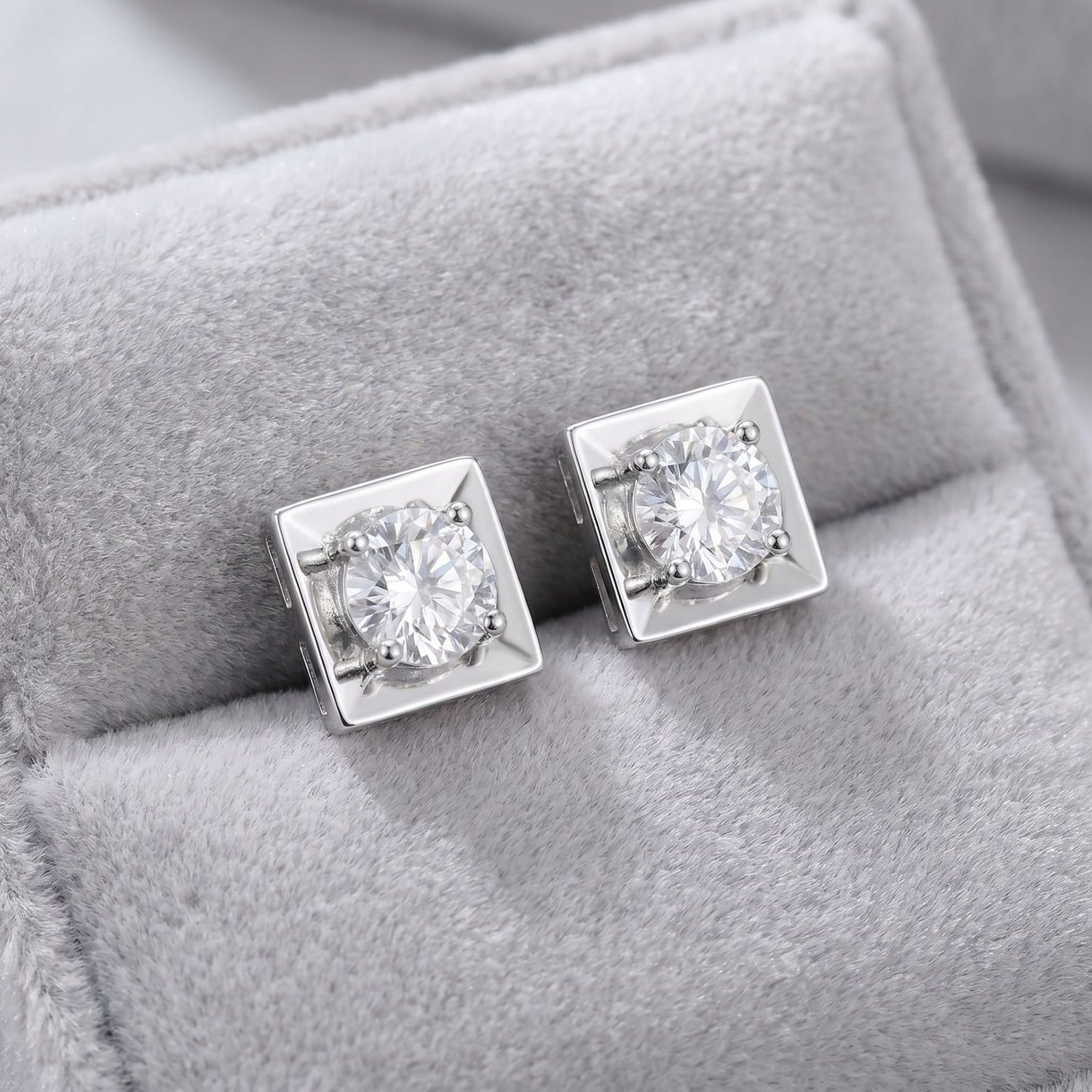 Square lab grown diamond stud earrings on a grey velvet cushion