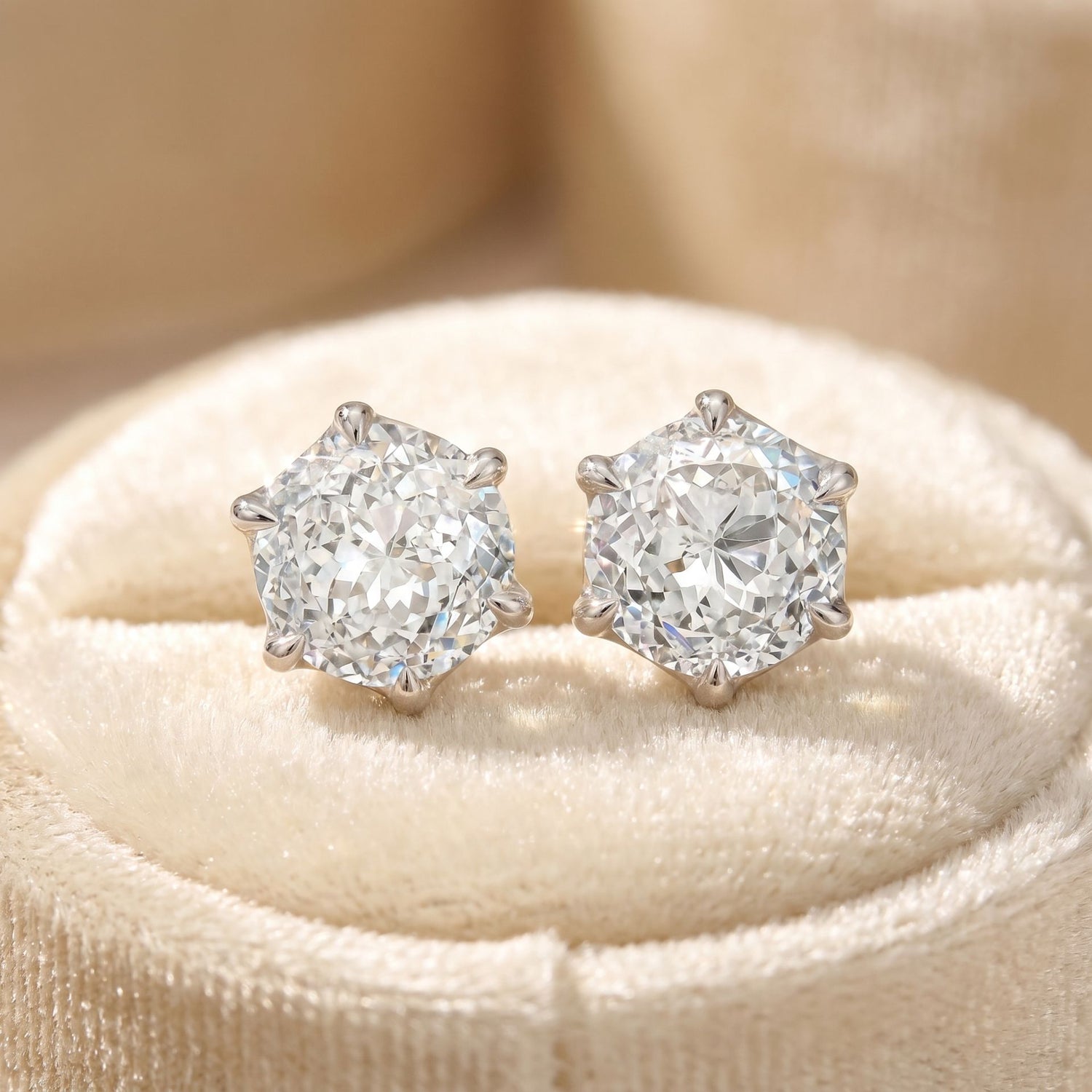 Lab grown diamond stud earrings on a beige velvet cushion