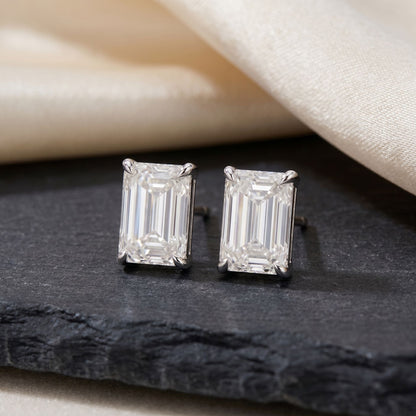 Emerald cut lab grown diamond stud earrings on a black stone display