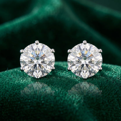 Pair of diamond stud earrings on a green fabric background