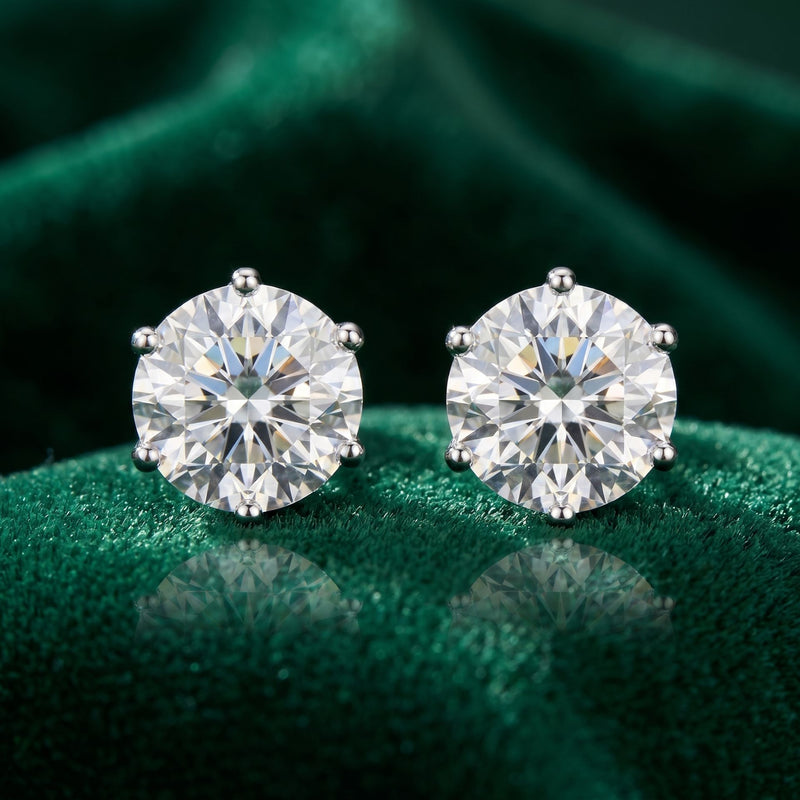 Pair of diamond stud earrings on a green fabric background