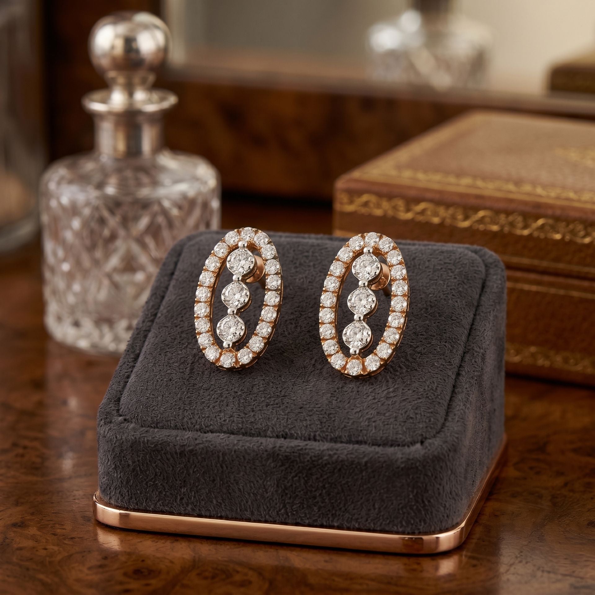 Pair of oval shape diamond earrings on a gray cushion with a wooden background