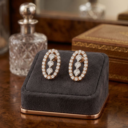 Pair of oval shape diamond earrings on a gray cushion with a wooden background