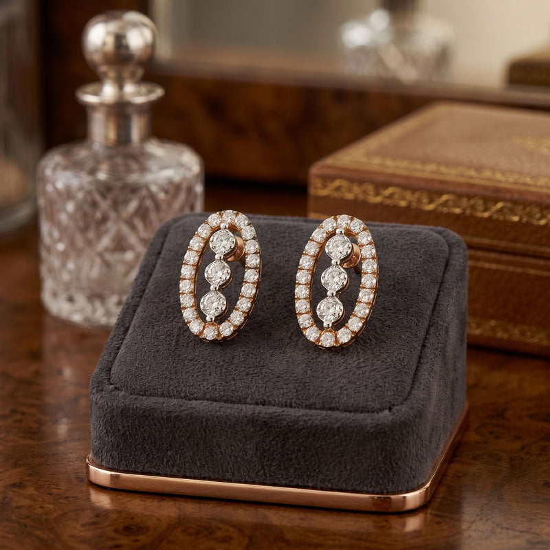 Pair of oval shape diamond earrings on a gray cushion with a wooden background