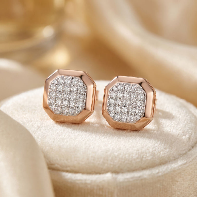 Rose gold earrings with diamond accents on a soft beige background