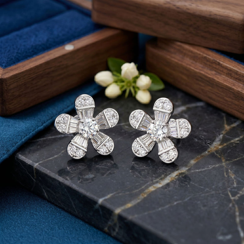 Floral lab-grown diamond stud earrings displayed on a wooden surface with green decorative accents.