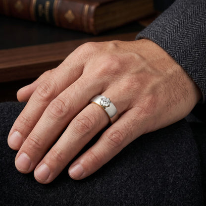 A hand wearing a classic brushed metal ring featuring a round solitaire lab-grown diamond in a secure prong setting on a dark textured surface.