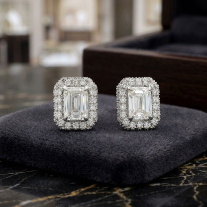 Pair of diamond earrings on a dark surface with a blurred background
