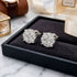 Pair of silver earrings on a black jewelry box with a marble surface background