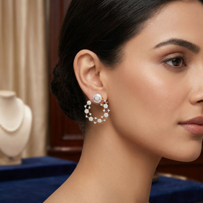 Close-up of a woman wearing diamond hoop earrings with a blurred jewelry store background.