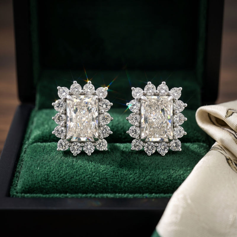 Pair of diamond earrings on a green cushion in a jewelry box.