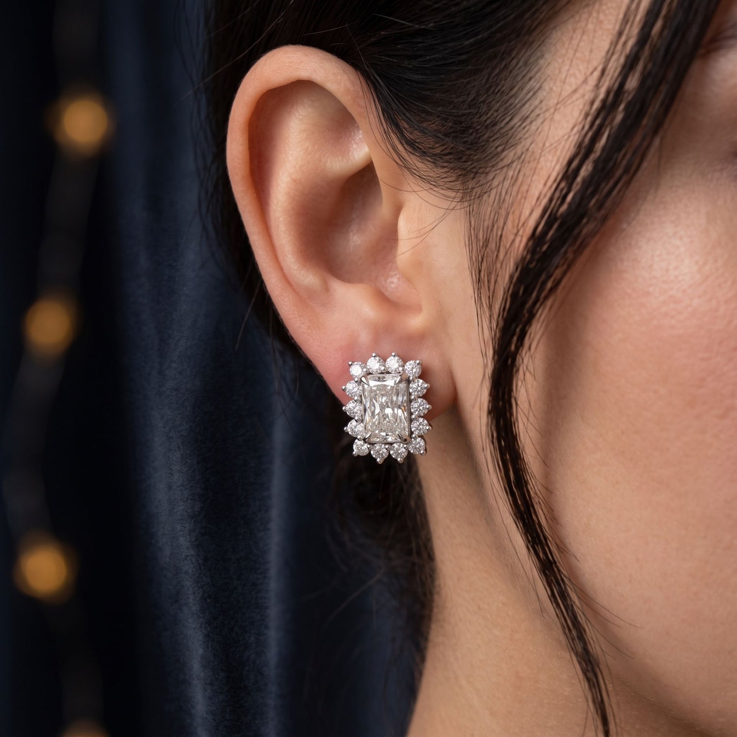 Close-up of an ear wearing a diamond earring with a blurred background