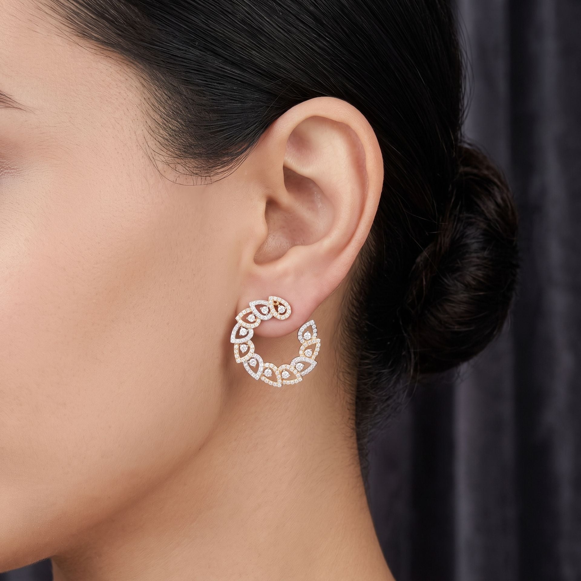 Close-up of a woman wearing a diamond hoop earring against a dark background