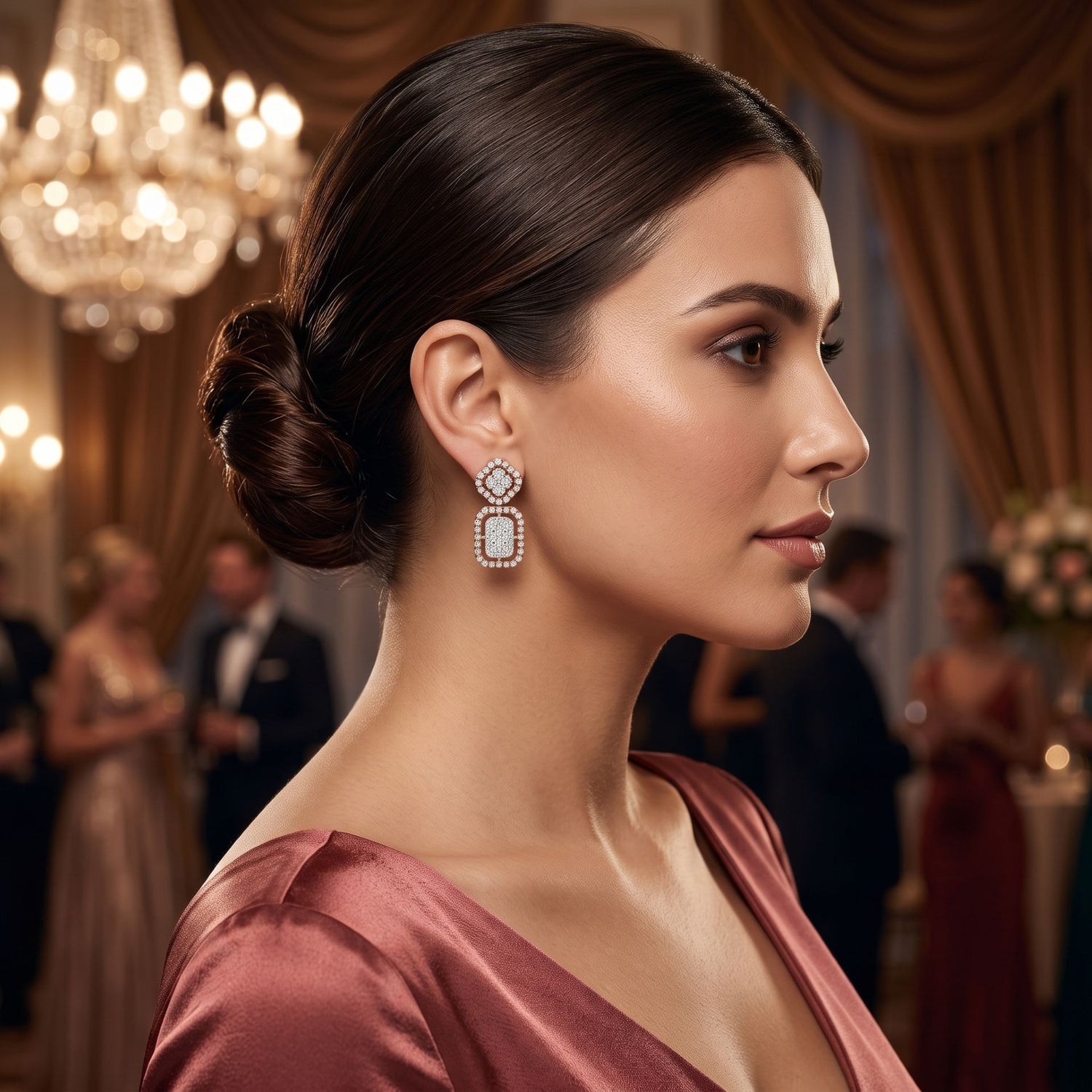 Woman wearing elegant earrings in a formal setting with chandeliers and people in the background